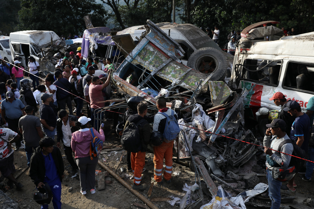 People gather around vehicles damaged in an attack on the Pan-American Highway in Cajibio, Colombia, Saturday, April 25, 2026, that killed at least a dozen people and authorities blamed on dissident groups of the former FARC rebels. (AP Photo/Santiago Saldarriaga)