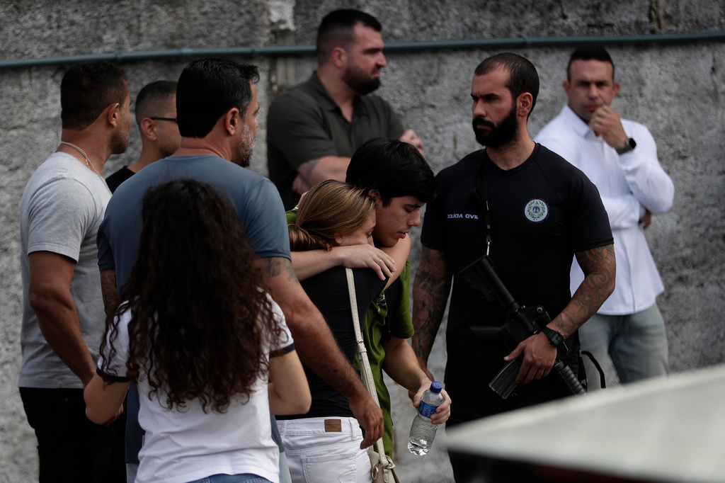People comfort each other near the site where two helicopters reportedly collided in midair and crashed into a car dealership parking lot in Rio de Janeiro, Brazil, Sunday, June 14, 2026. (AP Photo/Bruna Prado)