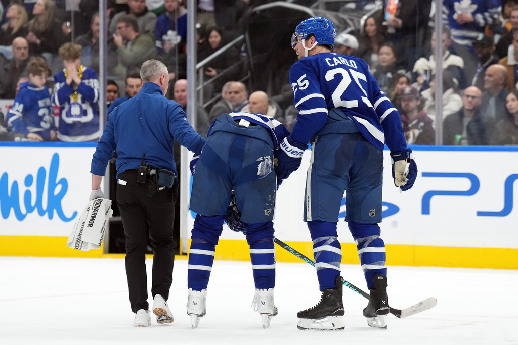 Toronto Maple Leafs Auston Matthews, center, is helped off the ice after being injured by Anaheim Ducks Radko Gudas during the second period of an NHL hockey game in Toronto, Thursday, March 12, 2026. (Nathan Denette/The Canadian Press via AP)