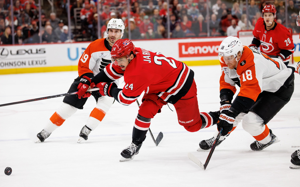 Carolina Hurricanes' Seth Jarvis (24) and Philadelphia Flyers' Rodrigo Abols (18) chase the puck during the second period of an NHL hockey game in Raleigh, N.C., Sunday, Dec. 14, 2025. (AP Photo/Ben McKeown)