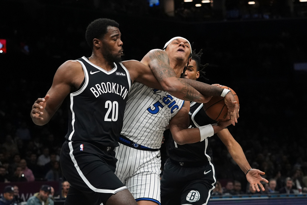Brooklyn Nets' Day'ron Sharpe (20) fights for control of the ball with Orlando Magic's Paolo Banchero (5) during the first half of an NBA basketball game Wednesday, Jan. 7, 2026, in New York. (AP Photo/Frank Franklin II)