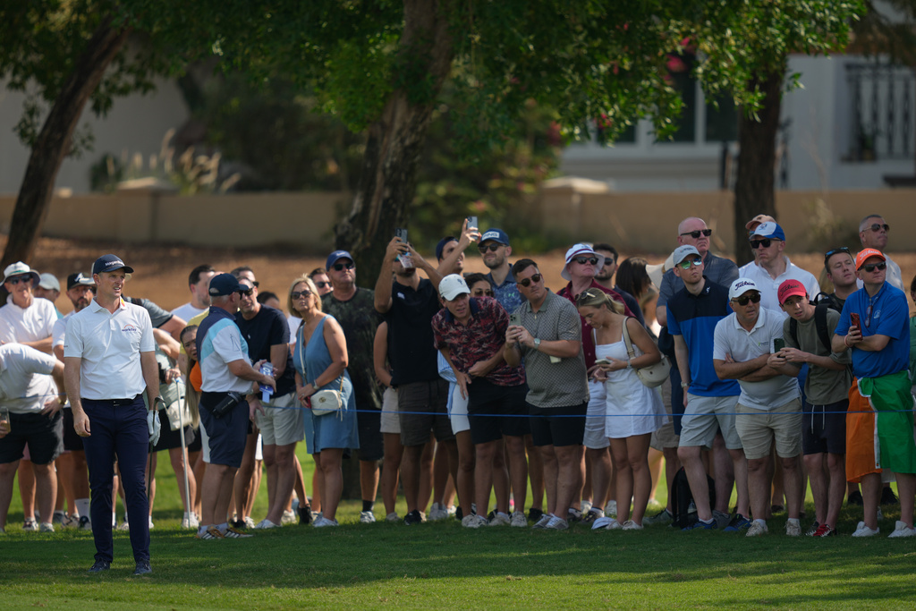 Spectators watch as Justin Rose of England plays his second shot on the 1st hole during the third round of World Tour Golf Championship at Jumeirah Golf Estates, in Dubai, United Arab Emirates, Saturday, Nov. 15, 2025. (AP Photo/Altaf Qadri)