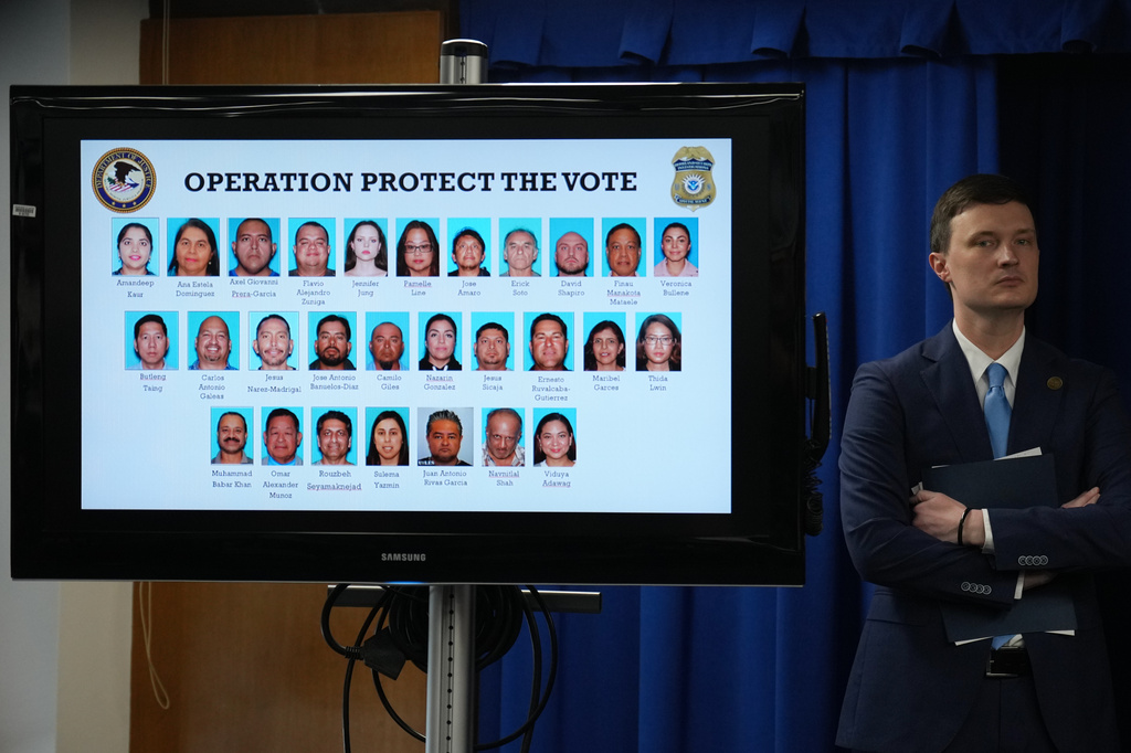 Acting U.S. Deputy Attorney General Trent McCotter stands next to a display showing photos of people charged with illegally registering to vote during a news conference in Los Angeles, Monday, Oct. 19, 2026. (AP Photo/Jae C. Hong)