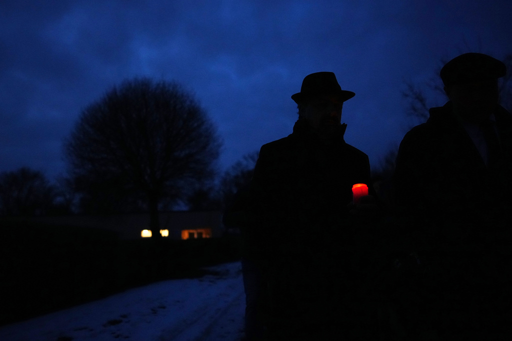 A man walks with a candle during the International Holocaust Remembrance Day at the former Nazi concentration camp in Terezin, Czech Republic, Tuesday, Jan. 27, 2026. (AP Photo/Petr David Josek)