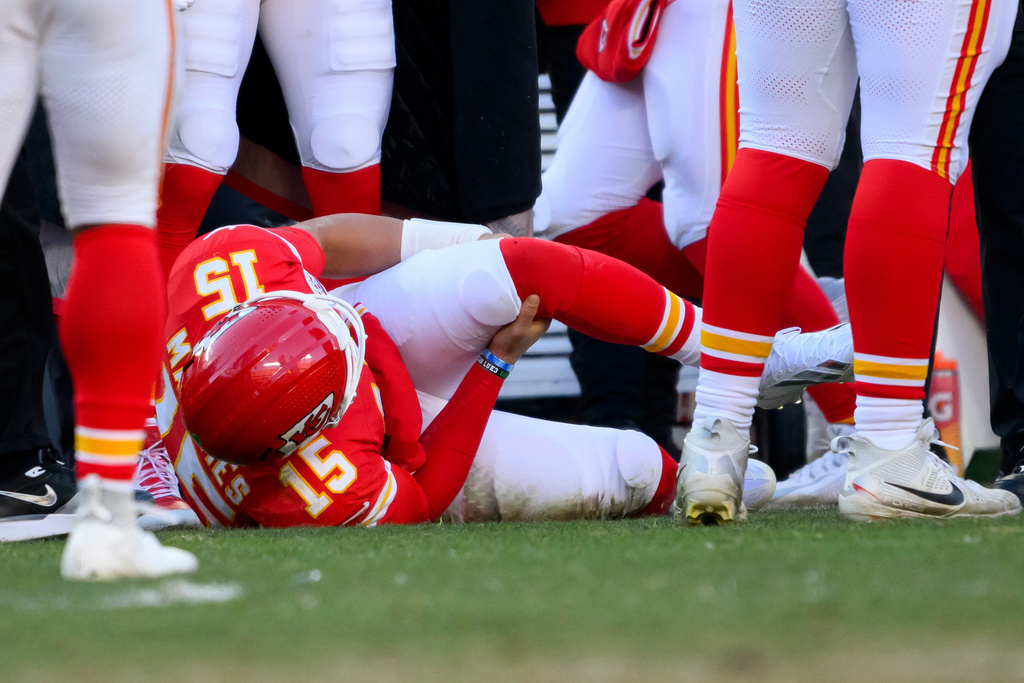 Kansas City Chiefs quarterback Patrick Mahomes grabs his knee after being injured during the second half of an NFL football game against the Los Angeles Chargers, Sunday, Dec. 14, 2025 in Kansas City, Mo. (AP Photo/Reed Hoffmann)