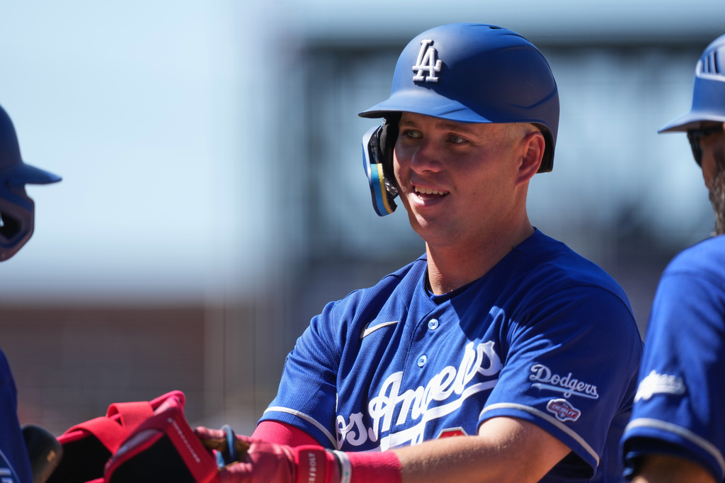 Los Angeles Dodgers' Ryan Ward hands over his batting apparel after reaching first base on a single off Colorado Rockies relief pitcher Antonio Senzatela in the sixth inning of a baseball game Sunday, April 19, 2026, in Denver. (AP Photo/David Zalubowski)