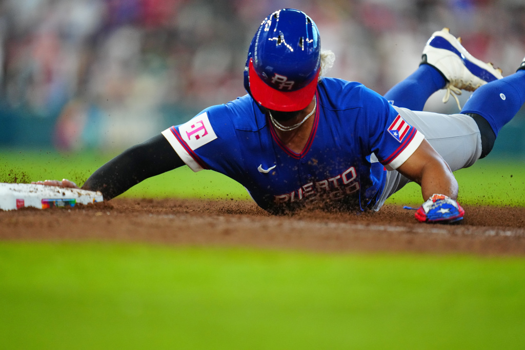 Puerto Rico's MJ Melendez dives back to first during the seventh inning of a World Baseball Classic quarterfinal game against Italy, Saturday, March 14, 2026, in Houston. (AP Photo/Karen Warren)