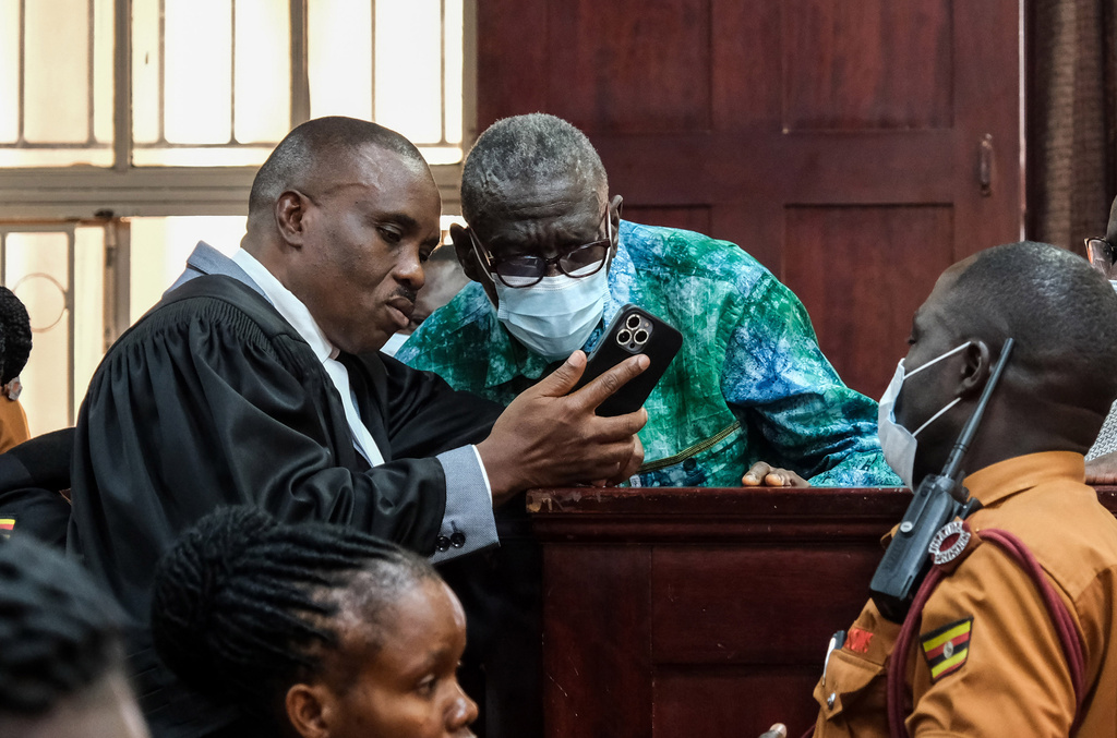 Uganda's veteran opposition leader Kizza Besigye, center, speaks with his lawyer Erias Lukwago, left, during a court session on a ruling on his bail application at the High Court in Kampala, Uganda, Monday, Dec. 29, 2025. (AP Photo/Hajarah Nalwadda)