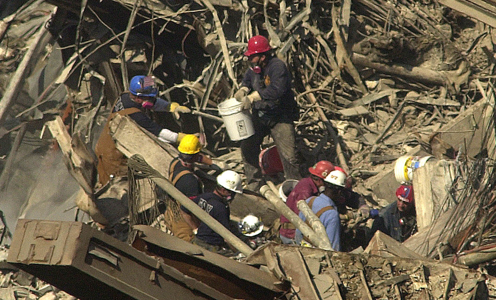 FILE - Firefighters use buckets to remove ash and dust from the wreckage of the World Trade Center in New York on Oct. 2, 2001. (AP Photo/LM Otero, File)