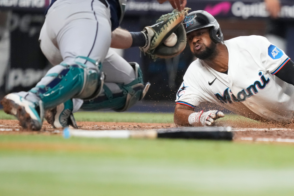 Miami Marlins' Otto Lopez, right, is tagged out at the plate by Seattle Mariners catcher Cal Raleigh, left, during the fifth inning of a baseball game, Wednesday, July 8, 2026, in Miami. (AP Photo/Lynne Sladky)