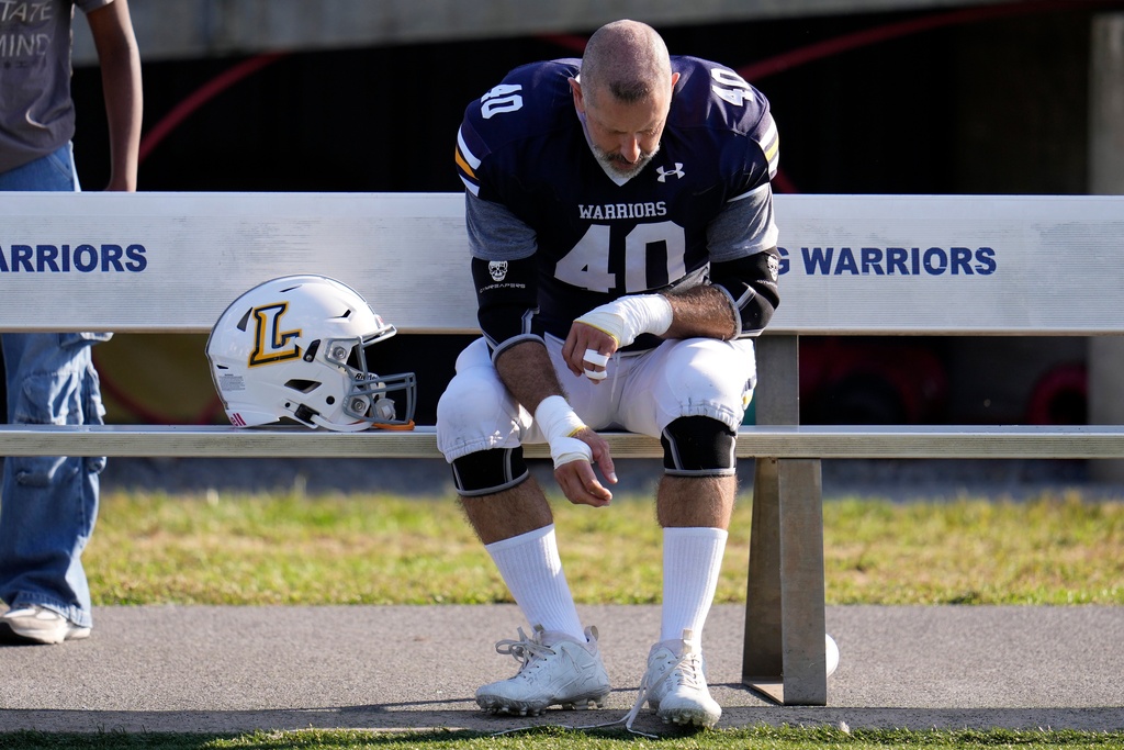After seeing his first college football game action Lycoming College nose tackle Tom Cillo loosens his shoe laces following a 23-16 win over King's College in an NCAA Division III college football game in Williamsport, Pa., Sunday, Sept. 28, 2025. (AP Photo/Gene J. Puskar)