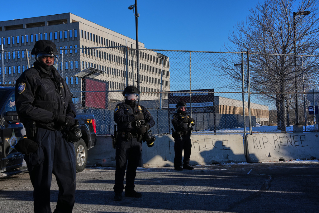 Federal immigration officers look on during a protest outside the Bishop Henry Whipple Federal Building, Friday, Jan. 30, 2026, in Minneapolis. (AP Photo/Adam Gray)