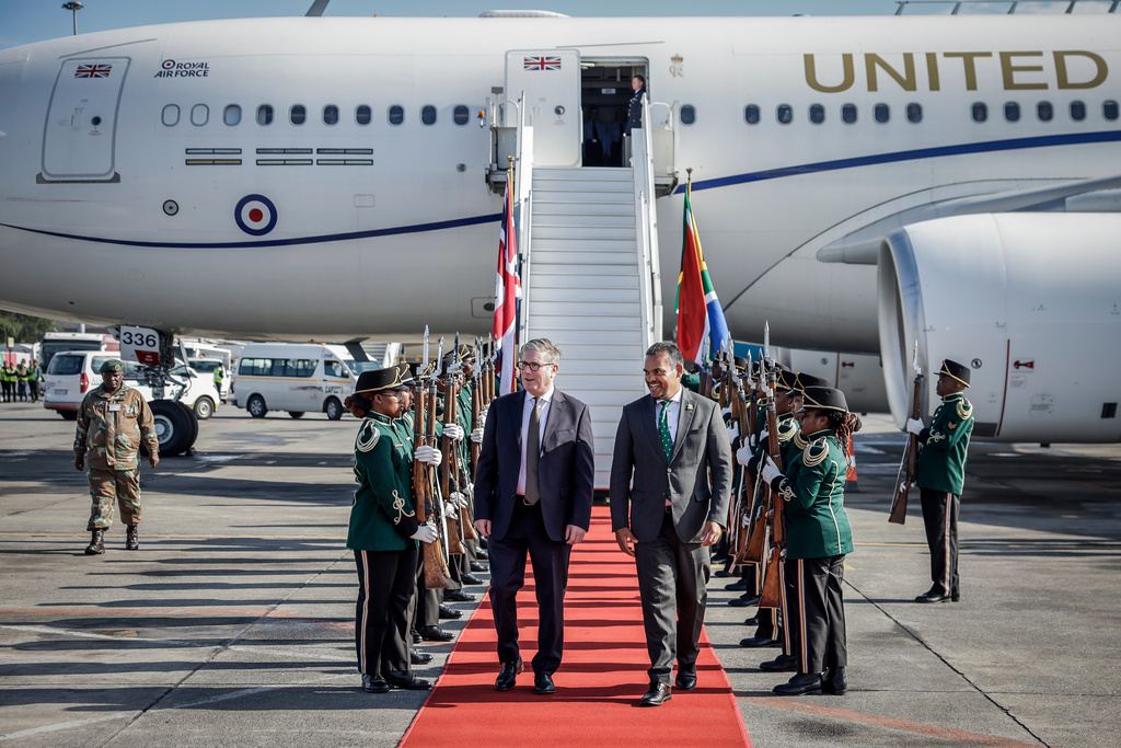 Britain's Prime Minister Keir Starmer, center left is welcomed by a South African representative upon his arrival at the OR Tambo International airport in Ekurhuleni on Friday, Nov. 21, 2025 ahead of the G20 leaders' Summit. ( Marco Longari /Pool Photo via AP)