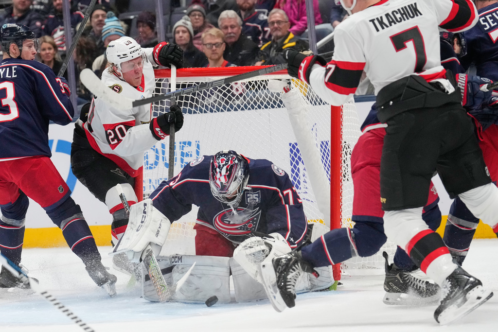 Columbus Blue Jackets goaltender Jet Greaves (73) covers the puck between Ottawa Senators left wing Fabian Zetterlund (20) and left wing Brady Tkachuk (7) in the second period of an NHL hockey game Thursday, Dec. 11, 2025, in Columbus, Ohio. (AP Photo/Sue Ogrocki)