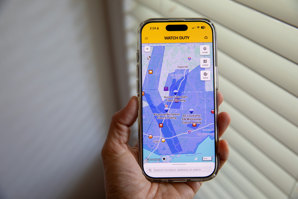 A person uses the Watch Duty app to track floods, Thursday, June 18, 2026, in San Diego, Calif. (AP Photo/Gabriela Aoun Angueira)