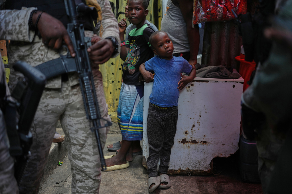 FILE - Children stand next to police officers during a visit from World Food Programme advisor Princess Sarah Zeid of Jordan at a shelter for families displaced by gang violence in Port-au-Prince, Haiti, Monday, April 27, 2026. (AP Photo/Odelyn Joseph, File)
