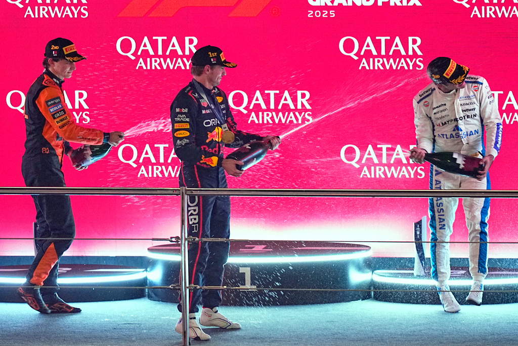 Winner Red Bull driver Max Verstappen of the Netherlands, centre, second placed McLaren driver Oscar Piastri of Australia, left, and third placed Williams driver Carlos Sainz of Spain celebrate on the podium after the Qatar Formula One Grand Prix, in Lusail, Qatar, Sunday, Nov. 30, 2025.(AP Photo/Fatima Shbair)