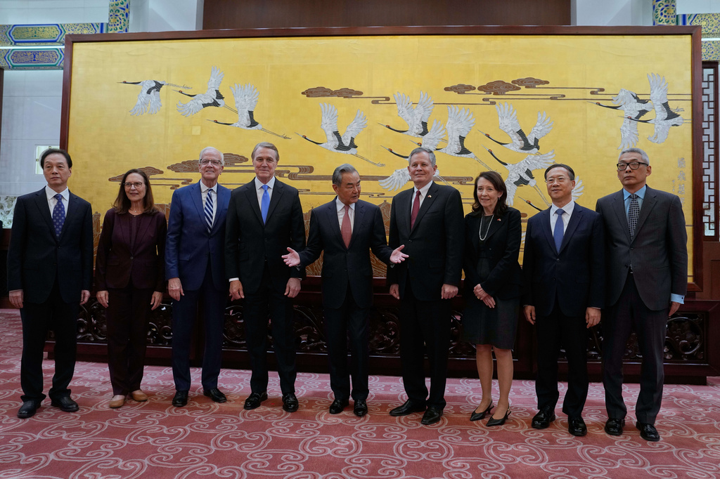 Chinese Foreign Minister Wang Yi, center, gestures next to U.S. Senator Steve Daines, center right, and U.S. Ambassador David Perdue, center left, after a group photo session with U.S. congressional delegation and Chinese delegation at the Great Hall of the People, in Beijing, Thursday, May 7, 2026. (AP Photo/Andy Wong, Pool)