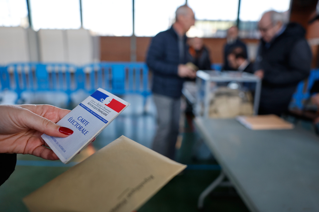 A woman holds a voting cart as she is about to castes her ballot during the first round of France's municipal elections in Henin-Beaumont, northern France, Sunday, March 15, 2026. (AP Photo/Jean-Francois Badias)
