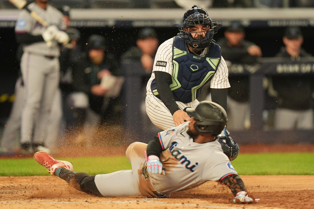 New York Yankees catcher Austin Wells, top, tags out Miami Marlins' Otto Lopez as he tries to score during the sixth inning of a baseball game, Sunday, April 5, 2026, in New York. (AP Photo/Seth Wenig)