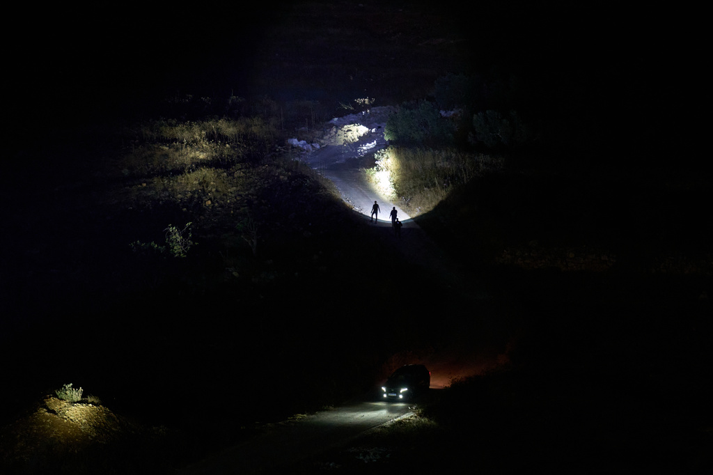 Palestinians use flashlights after spotting the presence of Israeli settlers on a hill as they take part in a night watch to protect their West Bank village of Sinjil, Thursday, July 16, 2026. (AP Photo/Leo Correa)