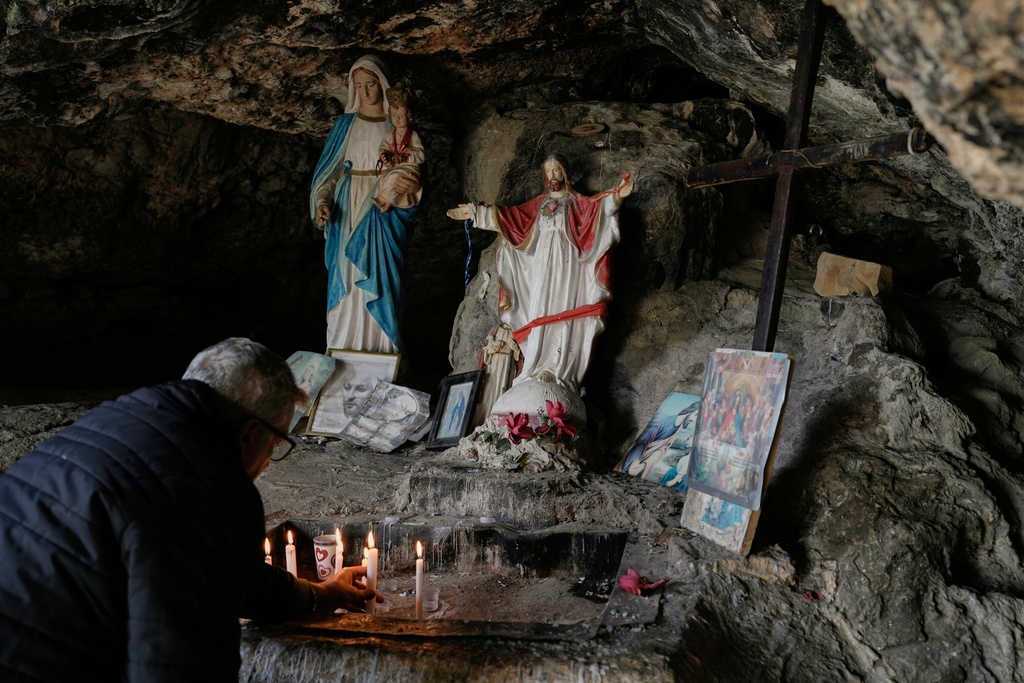 A man lights candles inside a cave that local tradition identifies as the site of Jesus Christ's first miracle, turning water into wine at a wedding feast, in the southern Lebanese village of Qana near the border with Israel, Lebanon, Sunday, Nov. 16, 2025. (AP Photo/Hassan Ammar)
