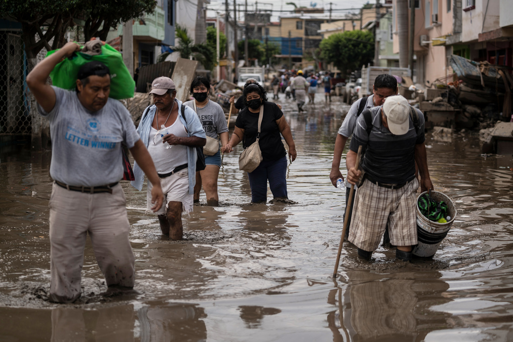People traverse a flooded street, in Poza Rica, Veracruz state, Mexico, Wednesday, Oct. 15, 2025, after torrential rain. (AP Photo/Felix Marquez)