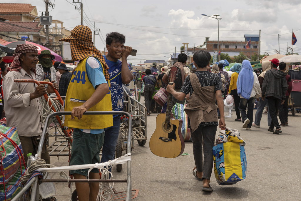 With a guitar in hand, a Cambodian migrant worker carries his belongings in Kamrieng, after crossing the Daung International Border Check Point between Cambodia and Thailand on Wednesday, Aug. 6, 2025. (AP Photo/Anton L. Delgado)