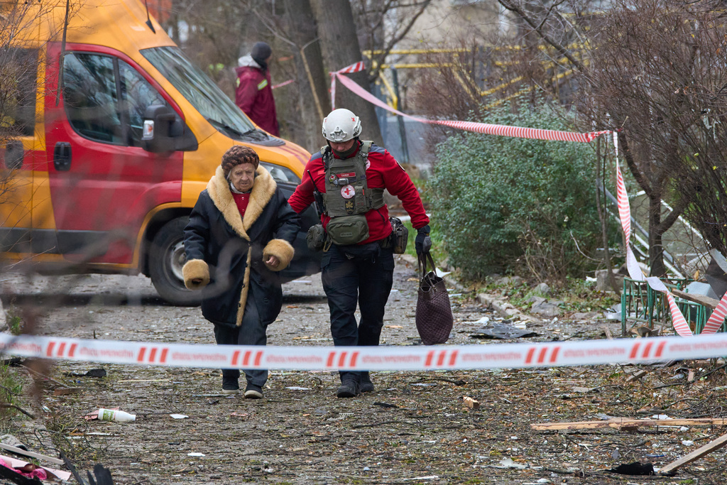 A paramedic evacuates an elderly resident after a Russian drone hit an apartment building during an aerial attack in Kyiv, Ukraine, Tuesday, Dec. 23, 2025. (AP Photo/Efrem Lukatsky)