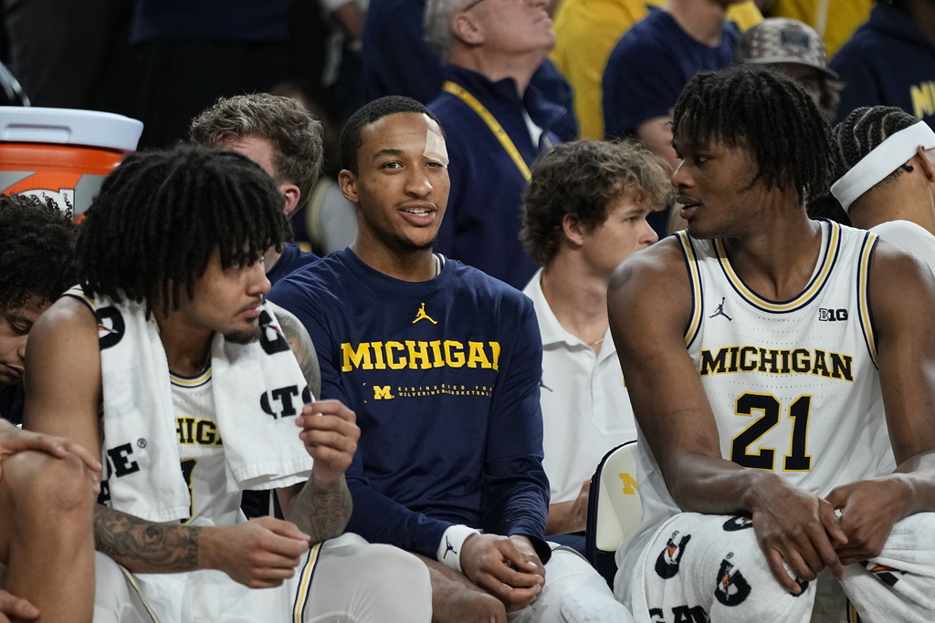 Michigan guard Nimari Burnett, center, sits with guard Elliot Cadeau, left, and forward Morez Johnson Jr., right, after an injury during the second half of an NCAA college basketball game against Southern California, Friday, Jan. 2, 2026, in Ann Arbor, Mich. (AP Photo/Ryan Sun)