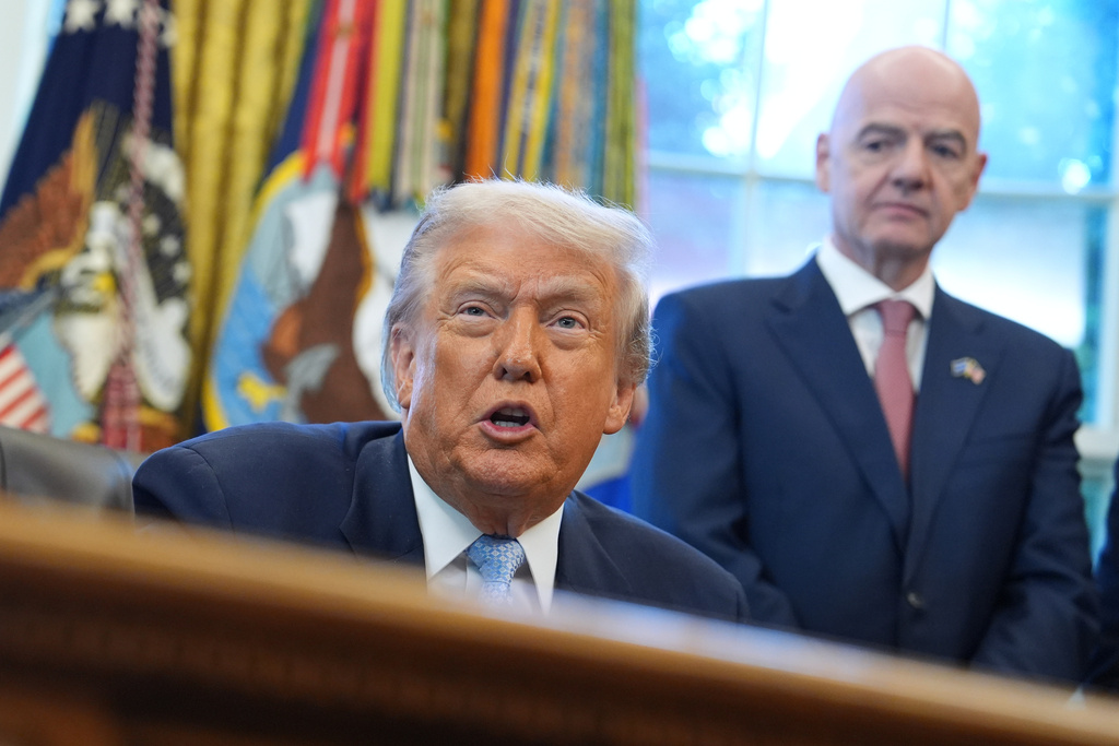 President Donald Trump answers questions from reporters during a meeting with the White House task force on the 2026 FIFA World Cup in the Oval Office of the White House, Monday, Nov. 17, 2025, in Washington, as FIFA President Gianni Infantino listens. (AP Photo/Evan Vucci)