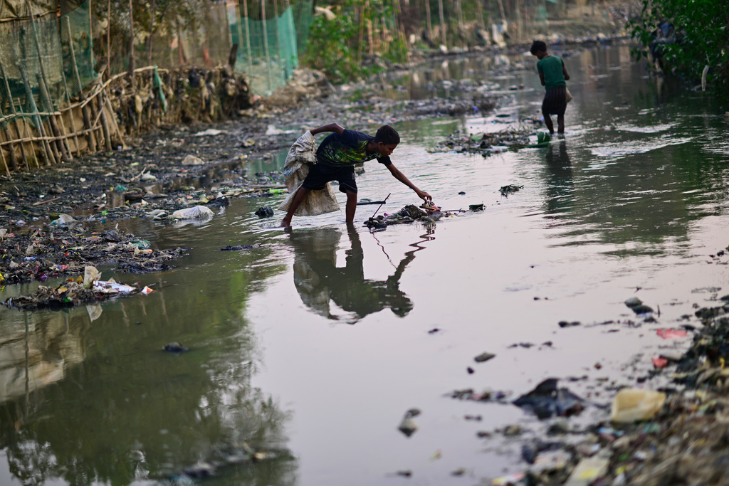 Thirteen-year-old Rohingya refugee Rahamot Ullah collects plastic waste from a drainage canal inside the Rohingya refugee camp in Cox's Bazar, Bangladesh, Saturday, Nov. 22, 2025. (AP Photo/Mahmud Hossain Opu)