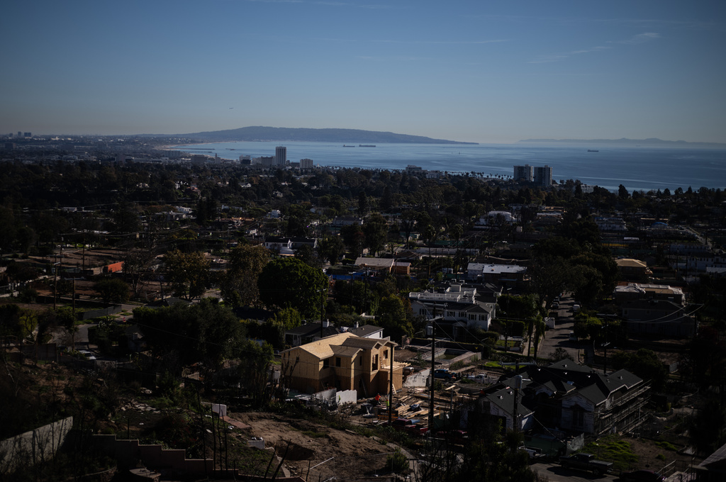 Homes being rebuilt after being destroyed by the Palisades Fire stand next to cleared lots, Tuesday, Dec. 9, 2025, in the Pacific Palisades neighborhood of Los Angeles. (AP Photo/Jae C. Hong)