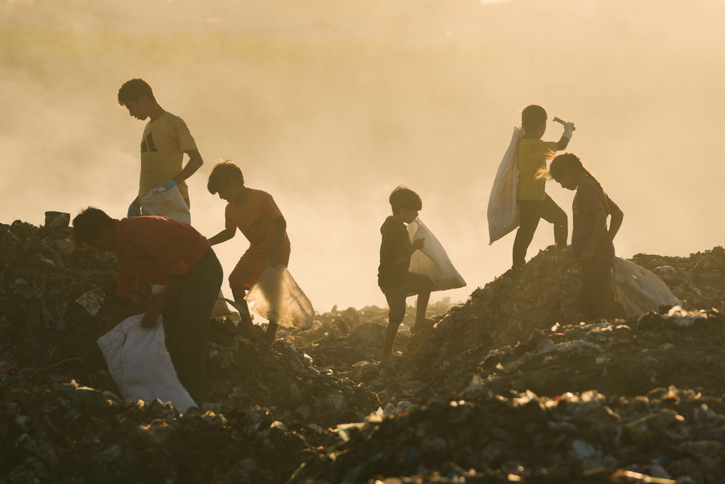 Displaced Palestinian children search for firewood and plastic in a landfill beside the makeshift tent camp where they are taking shelter, in Khan Younis, southern Gaza Strip, Tuesday, Sept. 30, 2025. (AP Photo/Jehad Alshrafi)