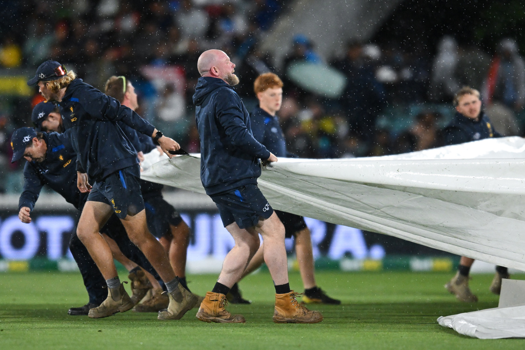 Ground staff pull the covers over the pitch as rain stops play during the T20 cricket international between India and Australia in Canberra, Australia, Wednesday, Oct. 29, 2025. (Lukas Coch/AAPImage via AP)