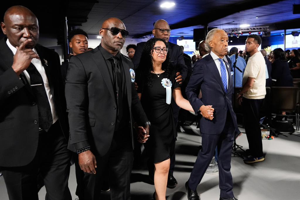 Christine Wonsley, center, walks with Rev. Al Sharpton, right, her husband Elmore, second from left, and attorney Ben Crump, left, during a memorial service for her son Nolan Xavier Wells, an 18-year-old found dead after taking a July 4 boat trip with friends, Monday, July 20, 2026, in Ocean Springs, Miss. (AP Photo/Gerald Herbert)