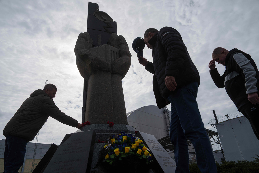Workers who helped clean up contamination from the Chernobyl nuclear power plant accident place flowers at a monument at the facility in Chernobyl, Ukraine, Tuesday, April 21, 2026. (AP Photo/Evgeniy Maloletka)