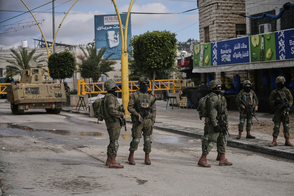 Israeli soldiers take up positions during an army raid in the West Bank city of Hebron Monday, Jan. 19, 2026. (AP Photo/Mahmoud Illean)
