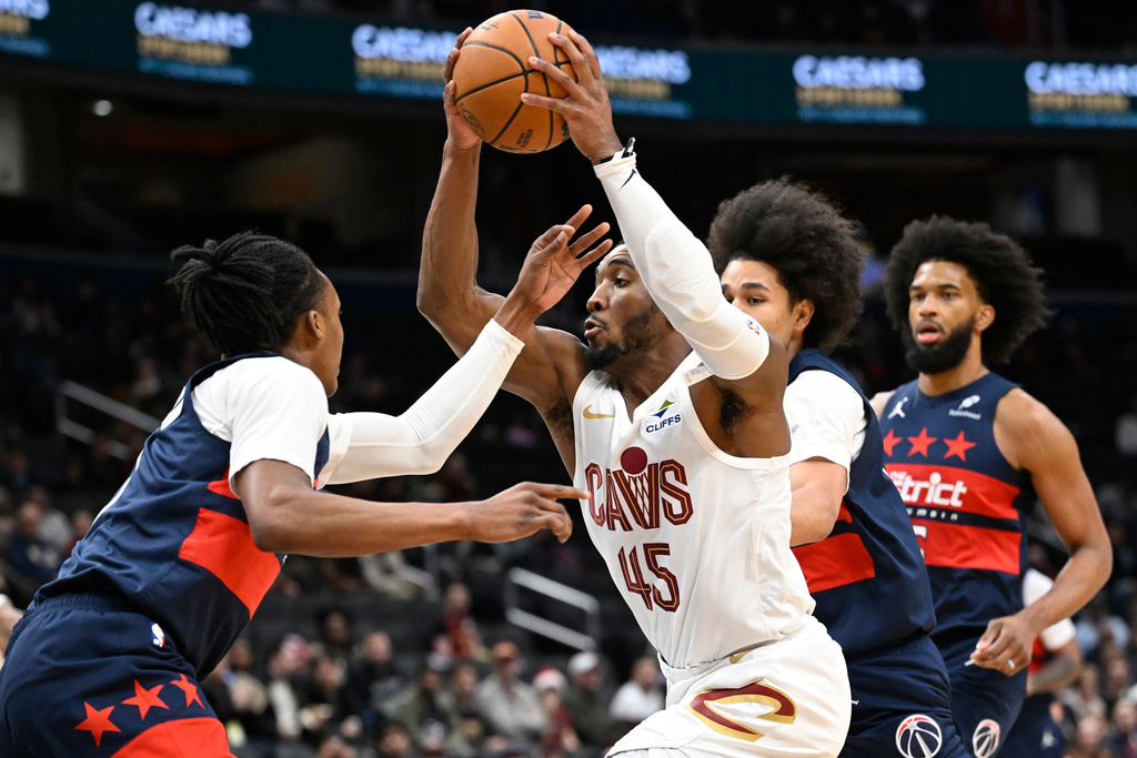 Cleveland Cavaliers guard Donovan Mitchell (45) prepare to shoot against Washington Wizards guard Bub Carrington, left, during the first half of an NBA basketball game Friday, Dec. 12, 2025, in Washington. (AP Photo/John McDonnell)
