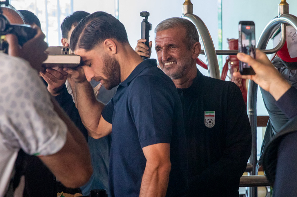 Iran national soccer team member Alireza Jahanbakhsh touches his forehead to the Quran while Mehdi Malekabad, Iranian Football Federation security manager stands by behind him at the Tijuana Marriott in Tijuana, Mexico on Saturday June 20, 2026. (AP Photo/Gabriela Aoun Angueira)