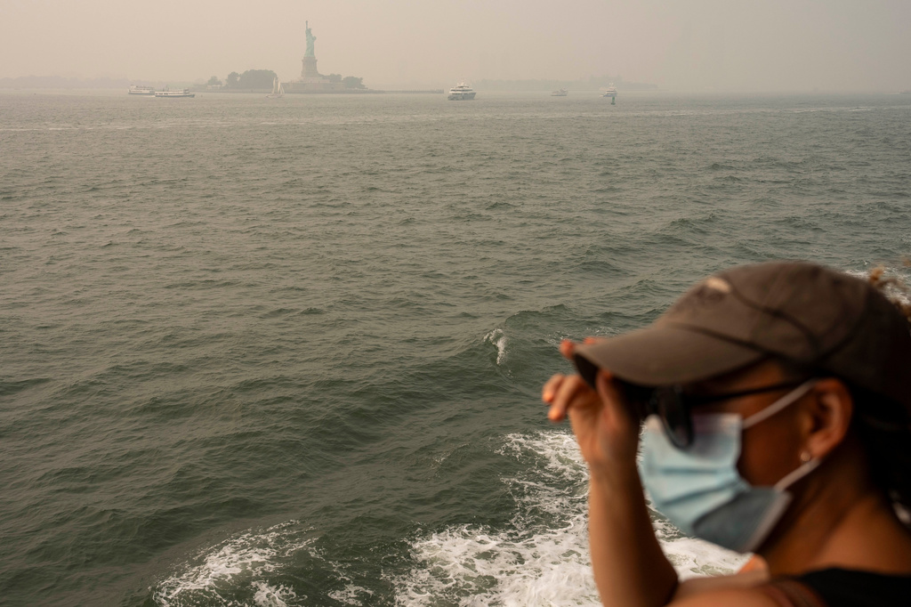 A person wearing a mask takes the Staten Island Ferry as as smoke from wildfires blankets the sky, Thursday, July 16, 2026, in New York. (AP Photo/Yuki Iwamura)