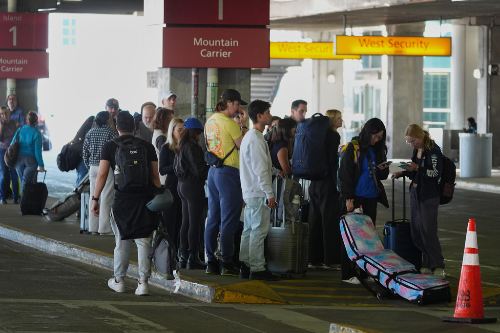 Travellers line up for transportation to mountain destinations outside Denver International Airport Friday, March 20, 2026, in Denver. (AP Photo/David Zalubowski)