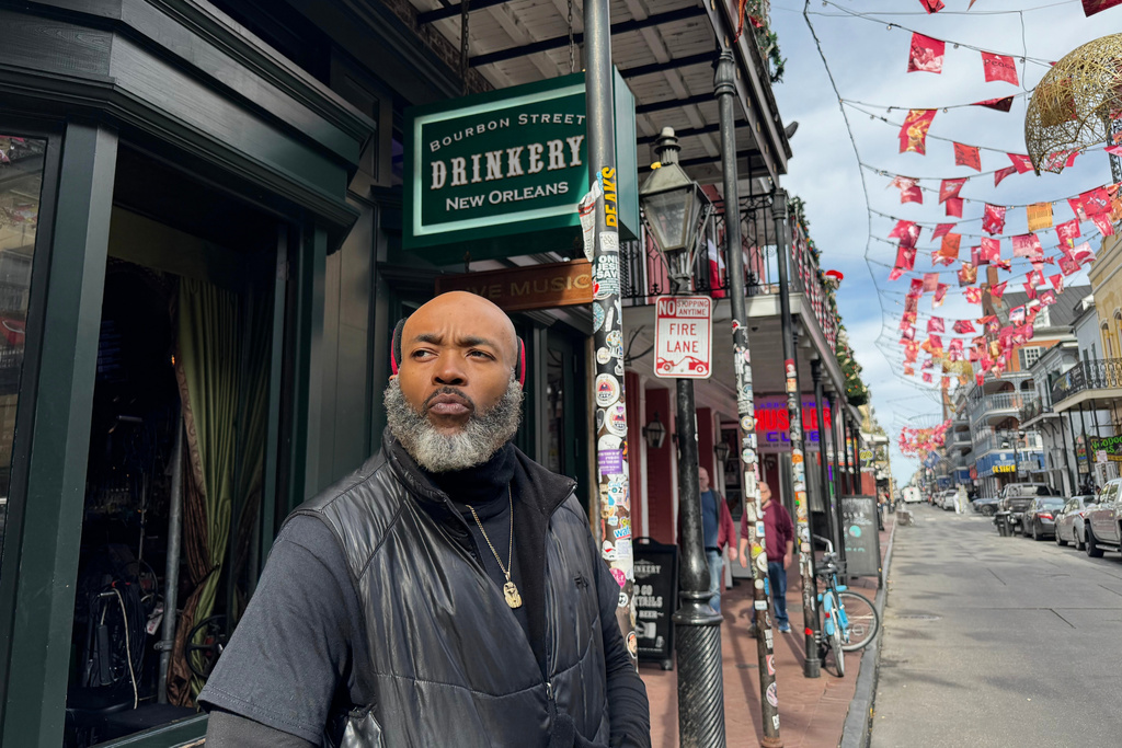 Miguel Thornton stands under memorial flags for the victims of a Jan. 1, 2025, vehicle ramming attack, outside of the Bourbon Street bar, where he works, on Monday, Dec. 29, 2025, in New Orleans. (AP Photo/Jack Brook)