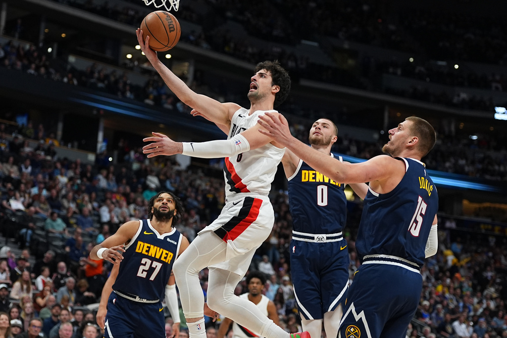 Portland Trail Blazers forward Deni Avdija, front left, drives to the basket past Denver Nuggets guard Christian Braun (0) and center Nikola Jokic, right, as Nuggets guard Jamal Murray (27) watches in the first half of an NBA basketball game Monday, April 6, 2026, in Denver. (AP Photo/David Zalubowski)