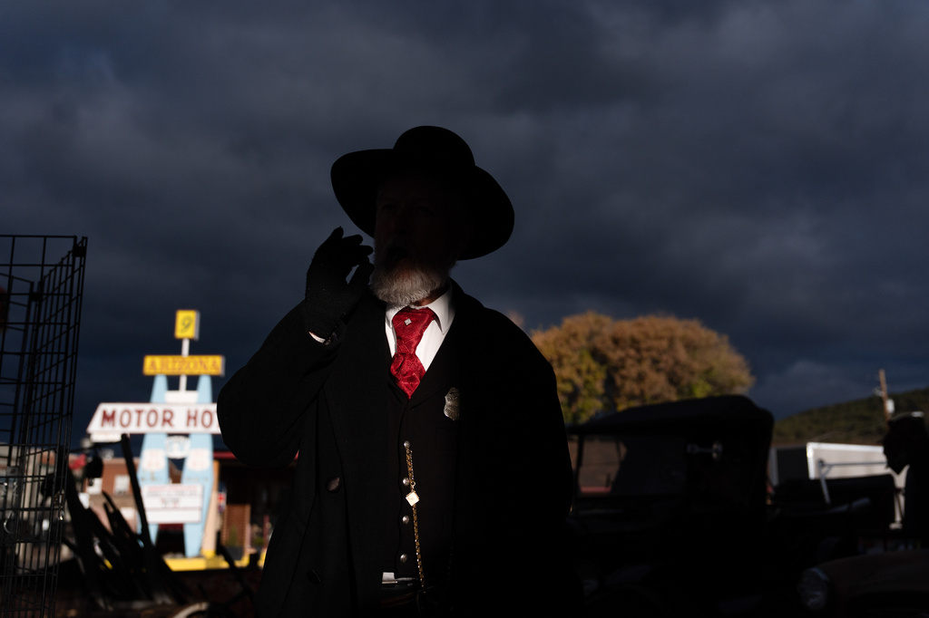 Jeff Smith, a part-time employee at a souvenir shop, smokes a cigar as a shaft of sunlight illuminates him in Williams, Ariz., a town on historic Route 66, Thursday, Nov. 20, 2025. (AP Photo/Jae C. Hong)