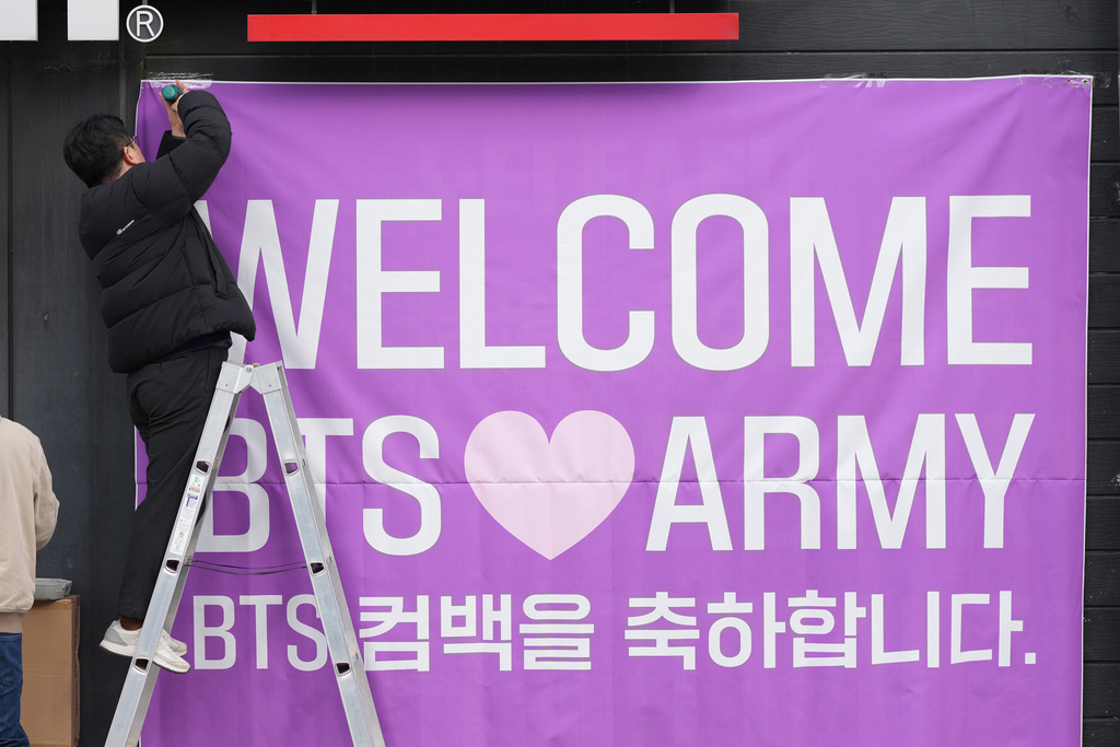 A man hangs a banner at a convenience store near the stage for a free concert by K-pop group BTS in Seoul, South Korea, March 18, 2026. (AP Photo/Lee Jin-man)