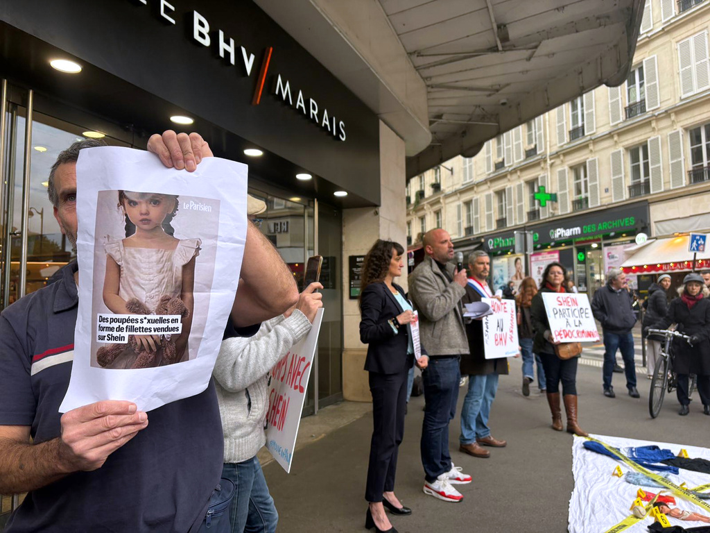 A protester holds a picture of a childlike sex doll outside BHV Marais department store in Paris, Monday, Nov. 3, 2025, where Shein is due to open its first permanent physical store world wide. (AP Photo/Nicolas Garriga)