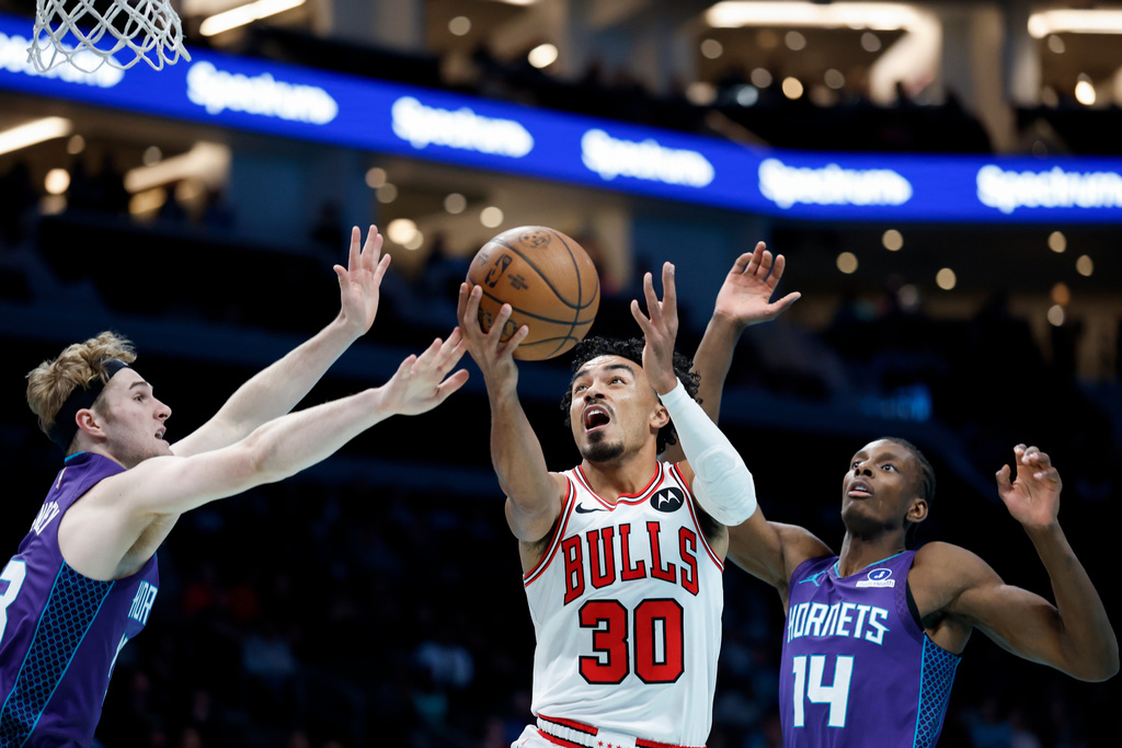Chicago Bulls guard Tre Jones (30) drives to the basket between Charlotte Hornets guard Liam McNeeley, left, and forward Moussa Diabate during the first half of an NBA Cup basketball game in Charlotte, N.C., Friday, Nov. 28, 2025. (AP Photo/Nell Redmond)