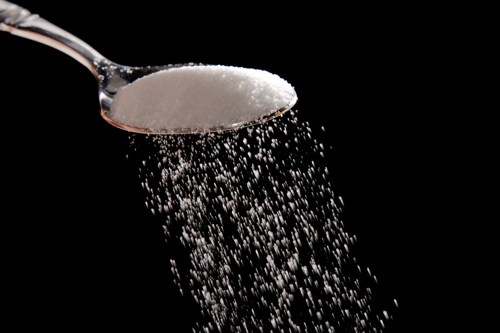 FILE - This photo illustration shows granulated sugar falling from a spoon, in Philadelphia, on Sept. 12, 2016. (AP Photo/Matt Rourke, File)
