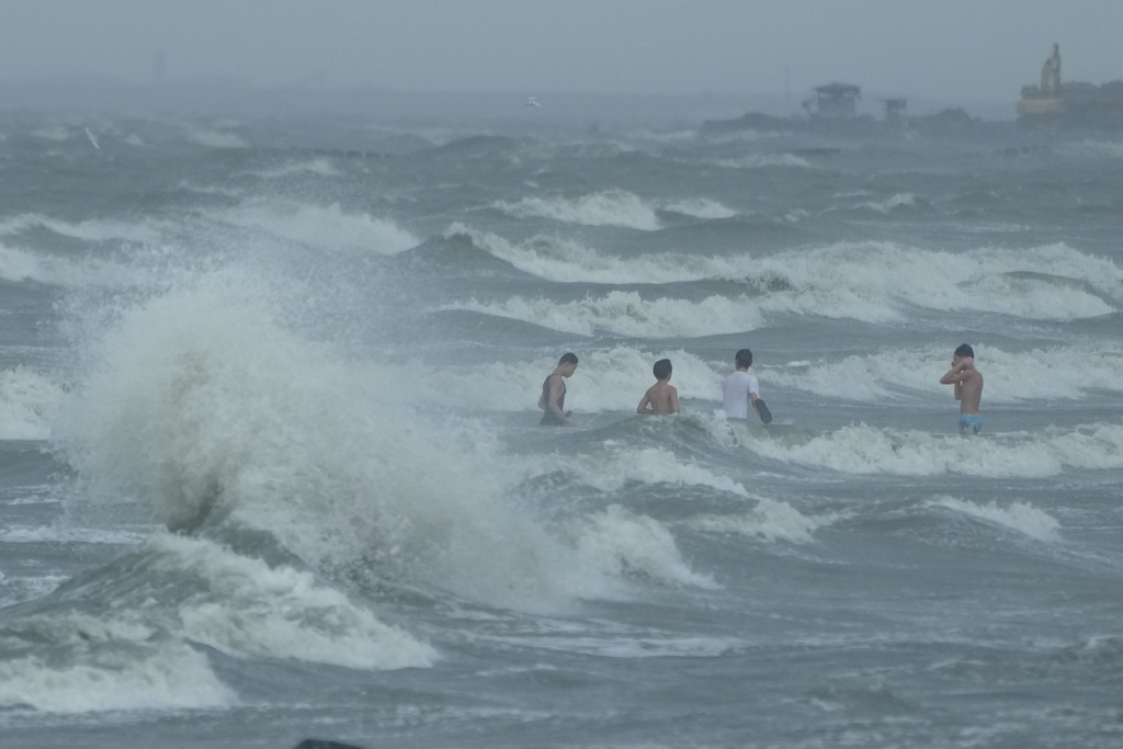 Men swim despite strong waves due to Typhoon Fung-wong along a coastal village on Monday, Nov. 10, 2025, in Navotas, Philippines. (AP Photo/Aaron Favila)